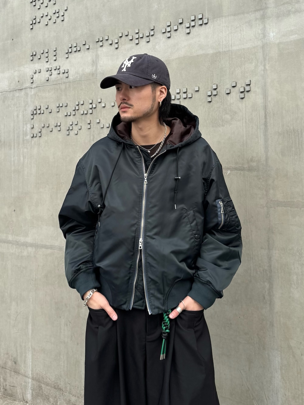 グリーン系のブルゾン、ブラック系のその他パンツ、ブラック系のキーホルダーを着用したメンズの冬コーディネートの6枚目の写真