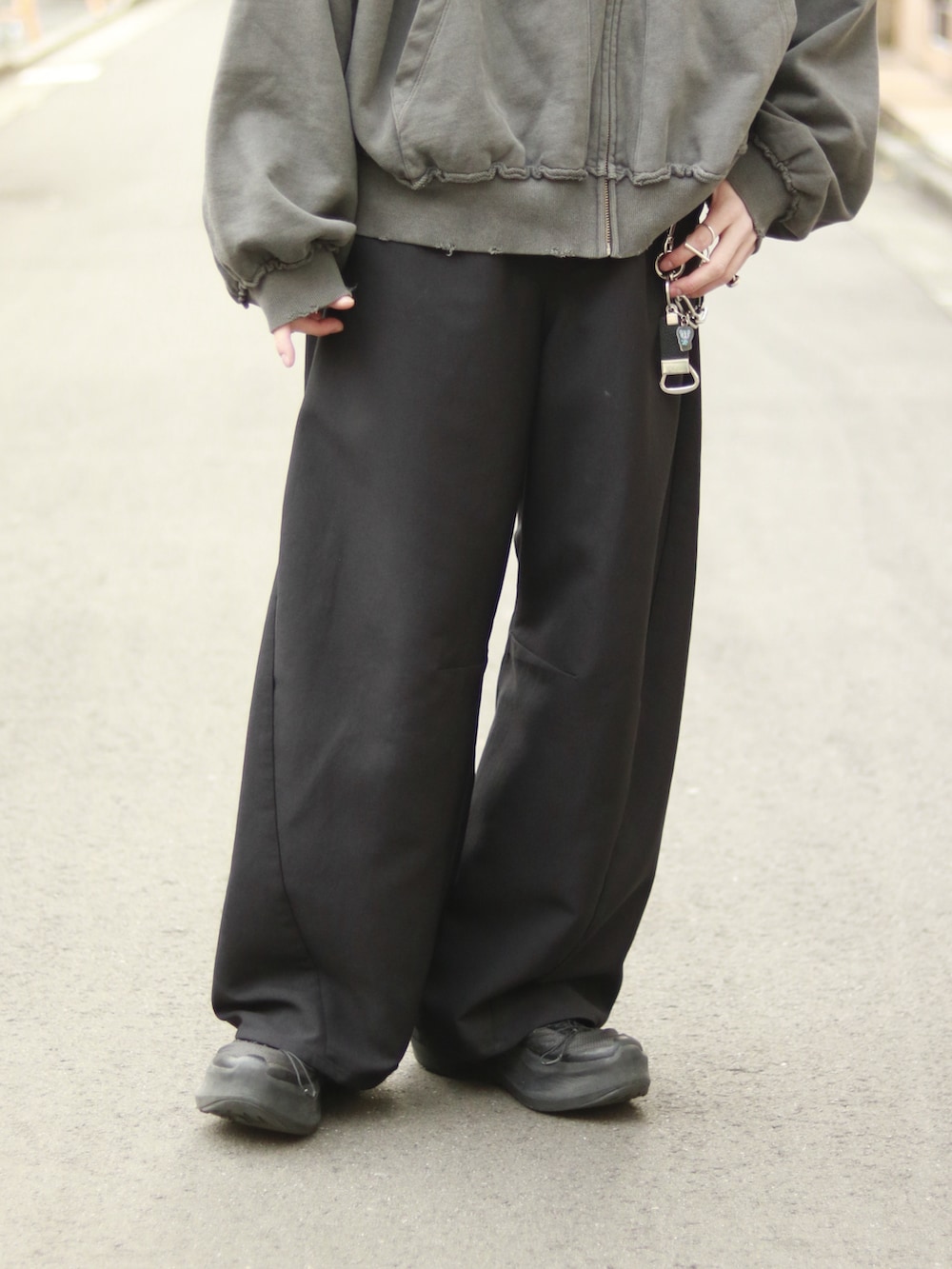 グレー系のパーカー、ブラック系のスラックス、ブラック系のキーホルダーを着用したメンズの冬コーディネートの5枚目の写真