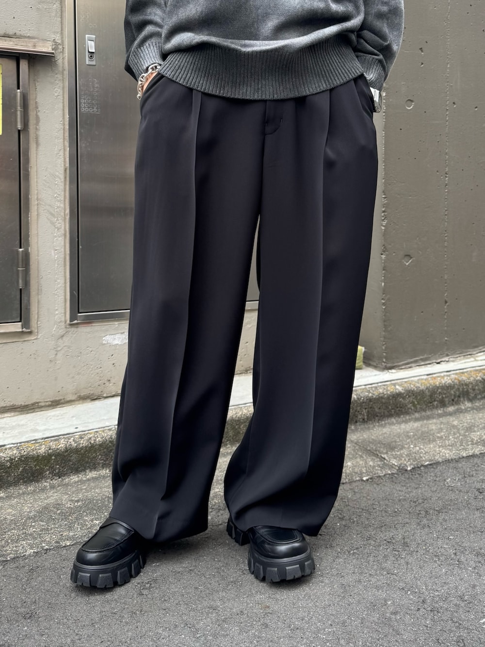 グレー系のニット/セーター、ブラック系のスラックスを着用したメンズの夏コーディネートの4枚目の写真