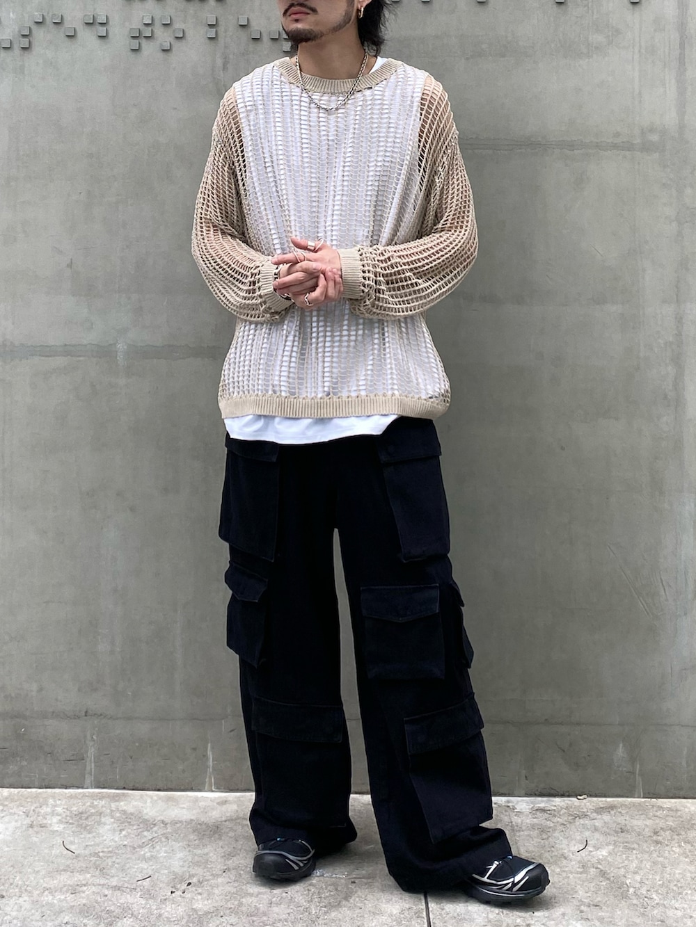 ベージュ系のニット/セーター、ホワイト系のタンクトップ、ブラック系のデニムパンツを着用したメンズの春コーディネートの2枚目の写真