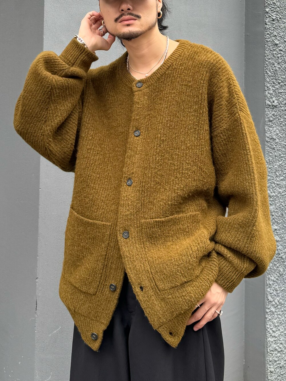 グリーン系のニット/セーター、ブラック系のパンツを着用したメンズの秋コーディネートの4枚目の写真