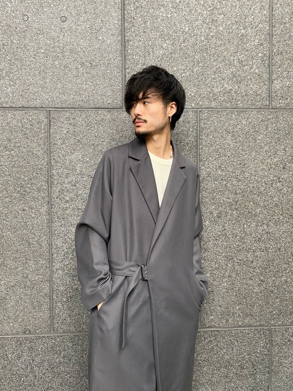 グレー系のトレンチコート、ベージュ系のデニムパンツ、ホワイト系のニット/セーターを着用したメンズの秋コーディネートの5枚目の写真