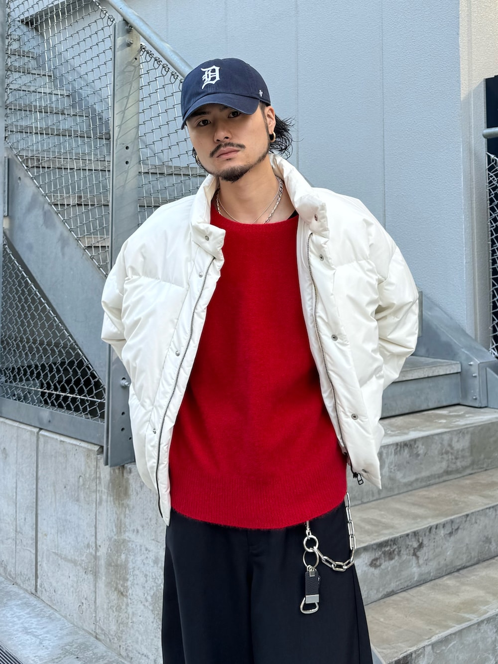 ホワイト系のブルゾン、ブラック系のスラックス、レッド系のニット/セーターを着用したメンズの冬コーディネートの5枚目の写真