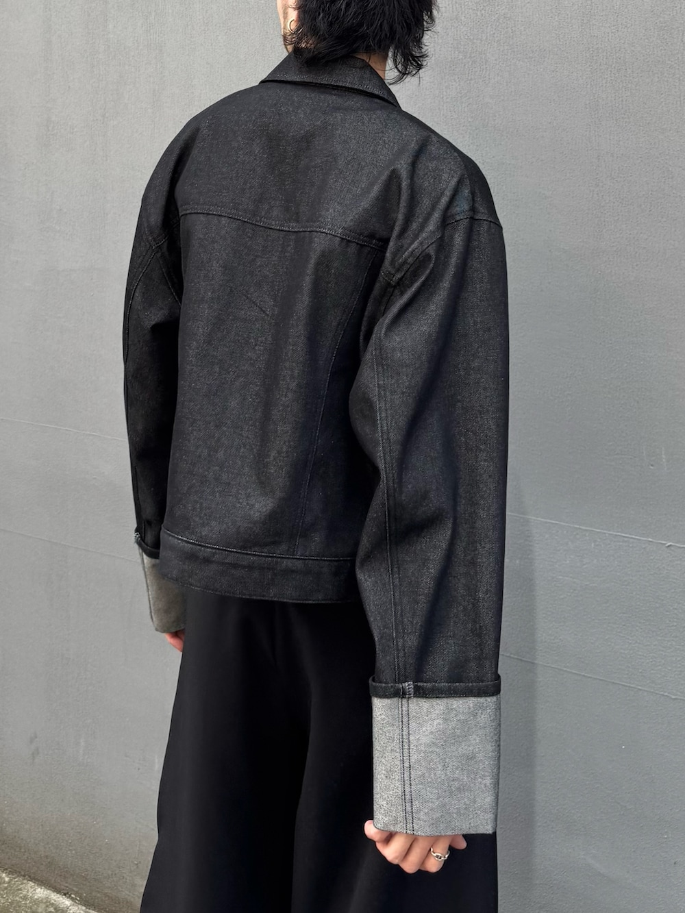 ブラック系のデニムジャケット、ブラック系のスラックス、ブラック系のウォレットチェーンを着用したメンズの春コーディネートの6枚目の写真