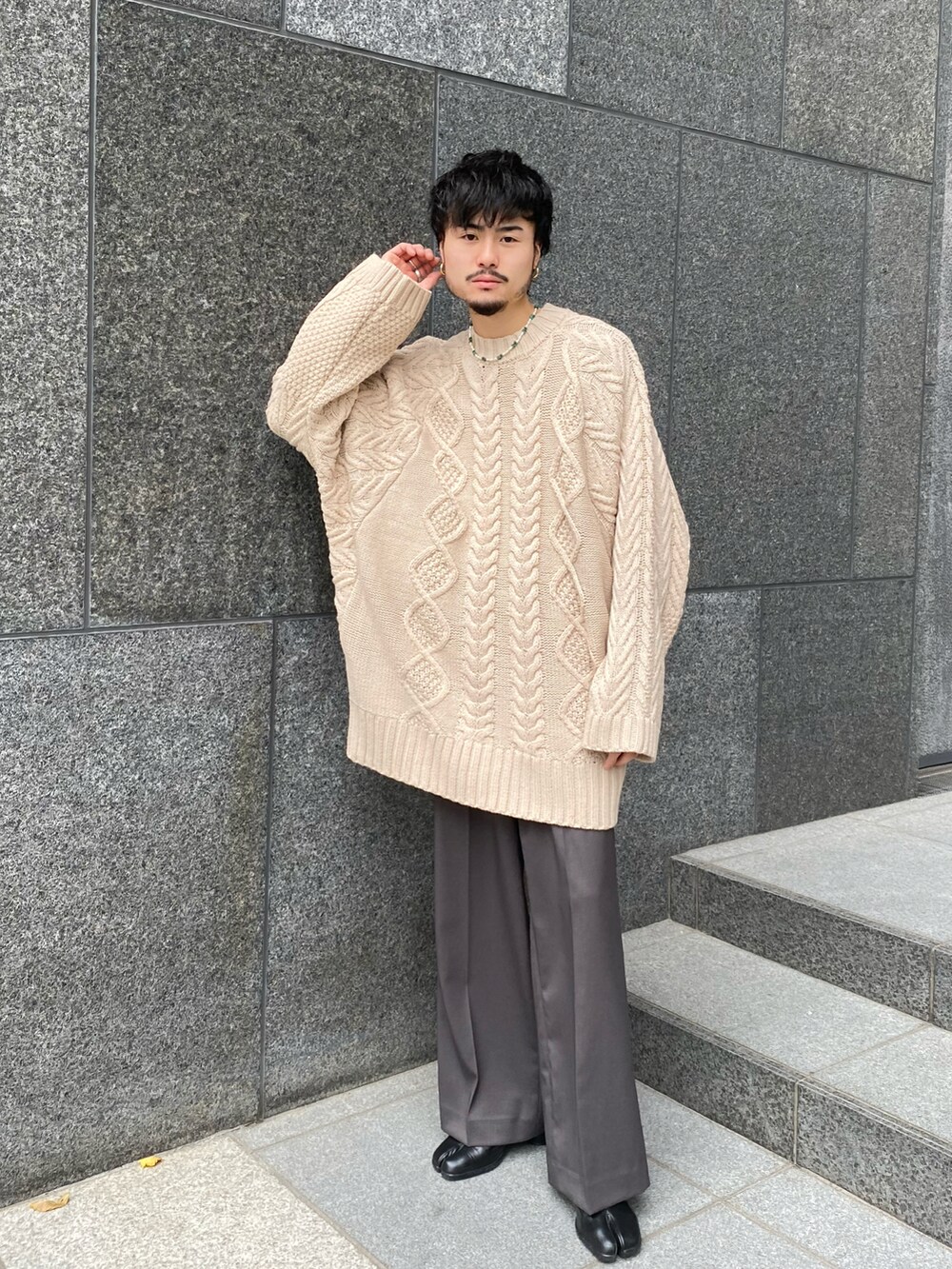 ホワイト系のニット/セーター、グレー系のスラックスを着用したメンズの冬コーディネートの2枚目の写真