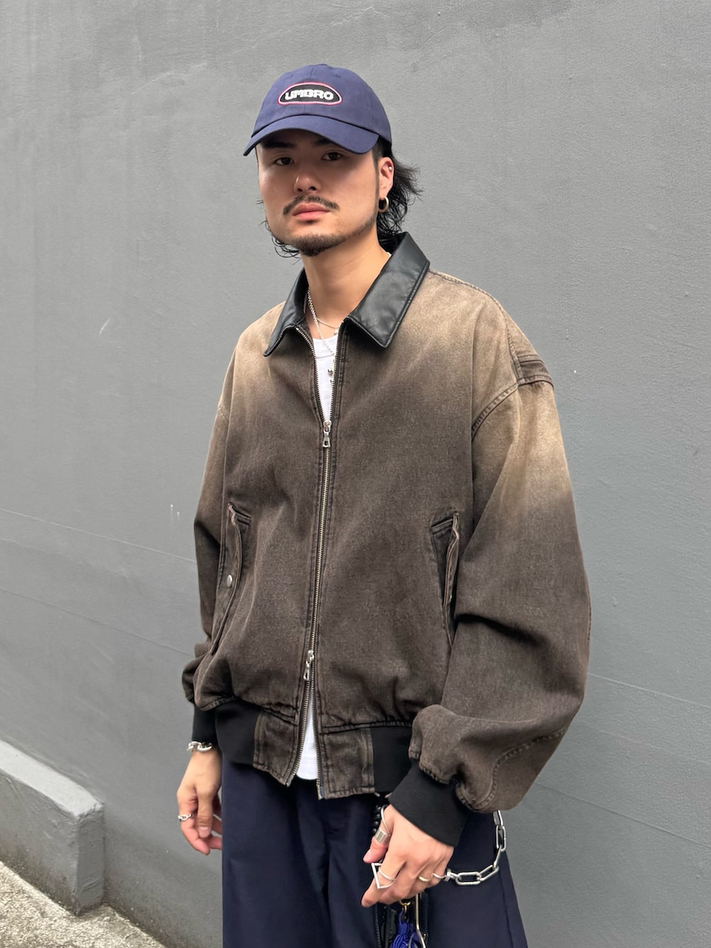 ブラウン系のデニムジャケット、ブルー系のスラックス、ブルー系のキャップを着用したメンズの秋コーディネートの5枚目の写真