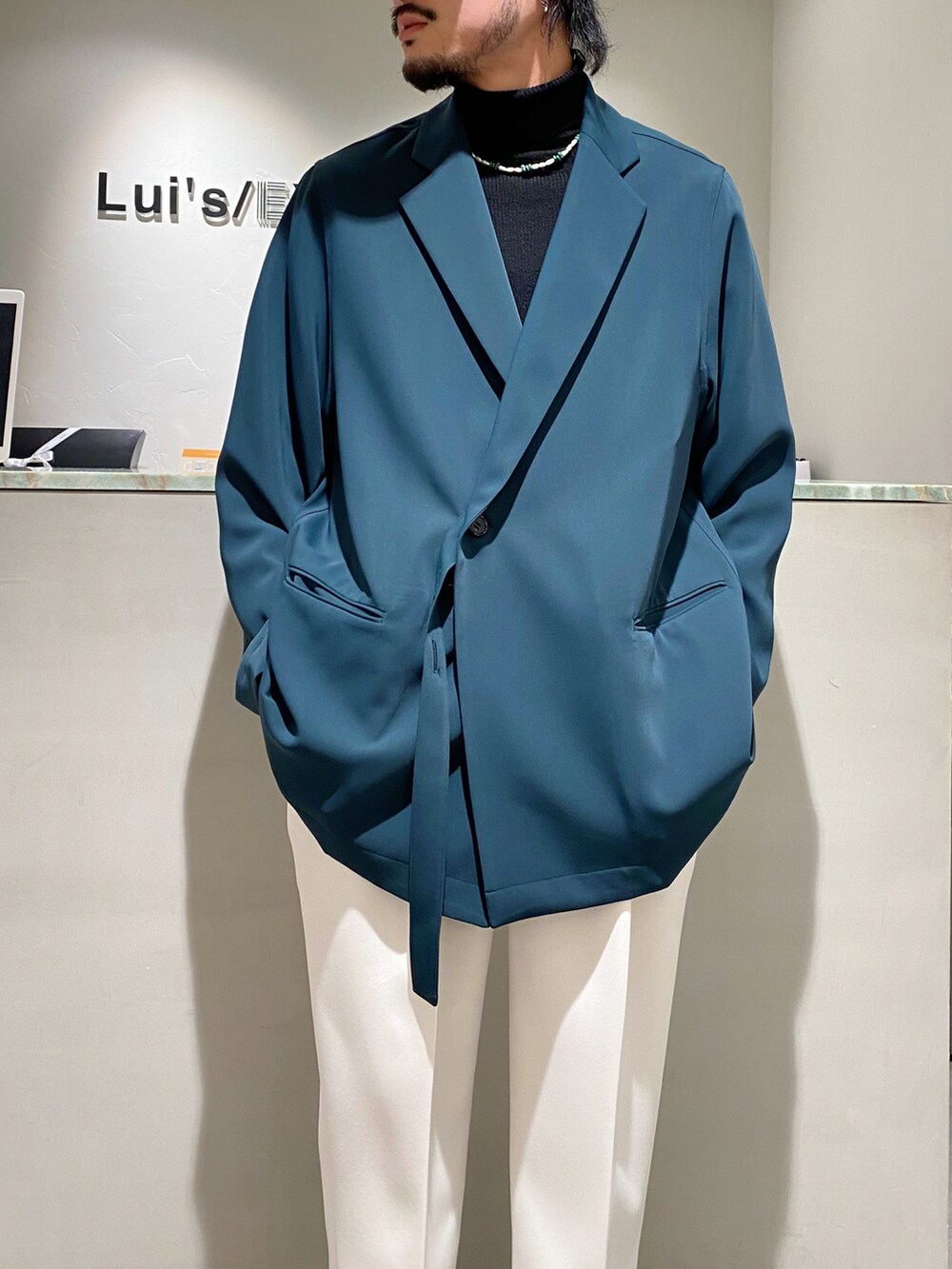 グリーン系のテーラードジャケット、ホワイト系のカーディガン/ボレロ、ホワイト系のスラックスを着用したメンズの春コーディネートの5枚目の写真