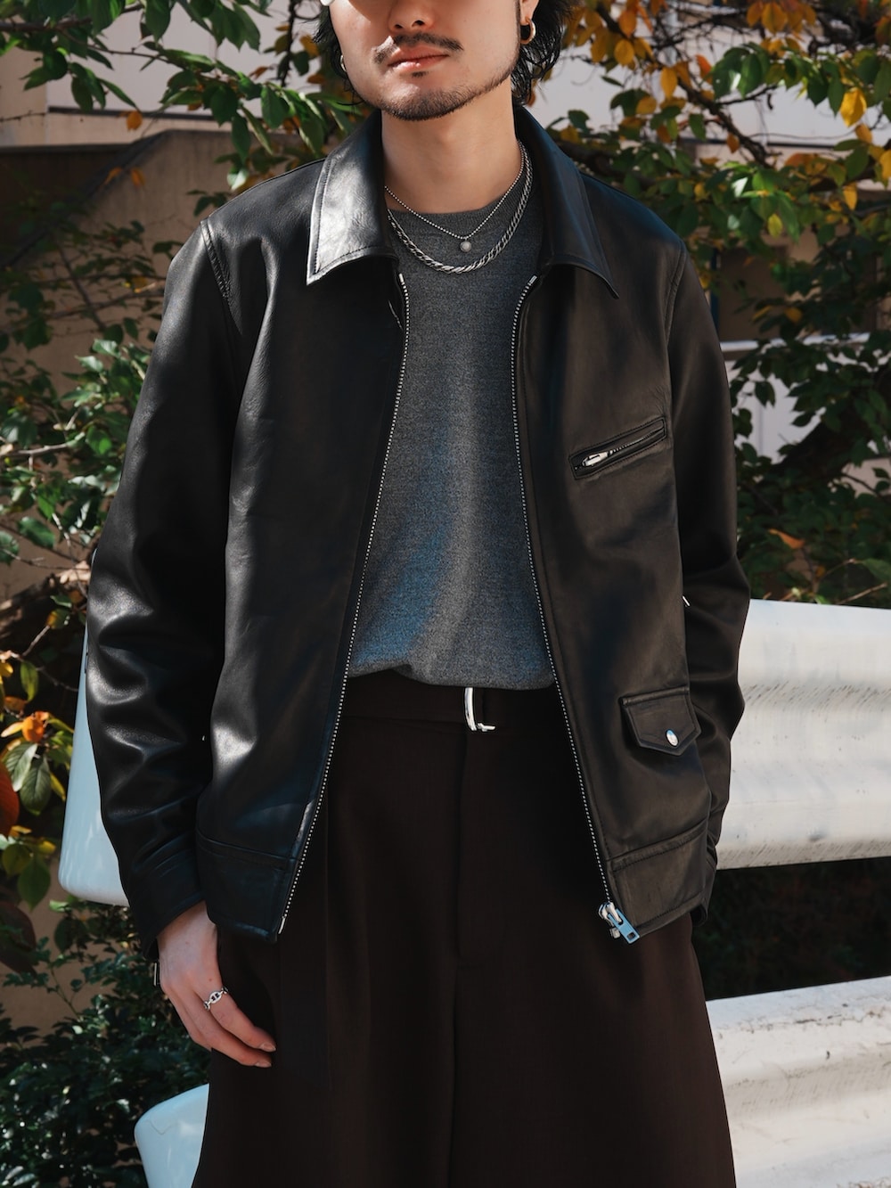 グレー系のスラックス、グレー系のニット/セーター、ブラック系のライダースジャケットを着用したメンズの冬コーディネートの5枚目の写真