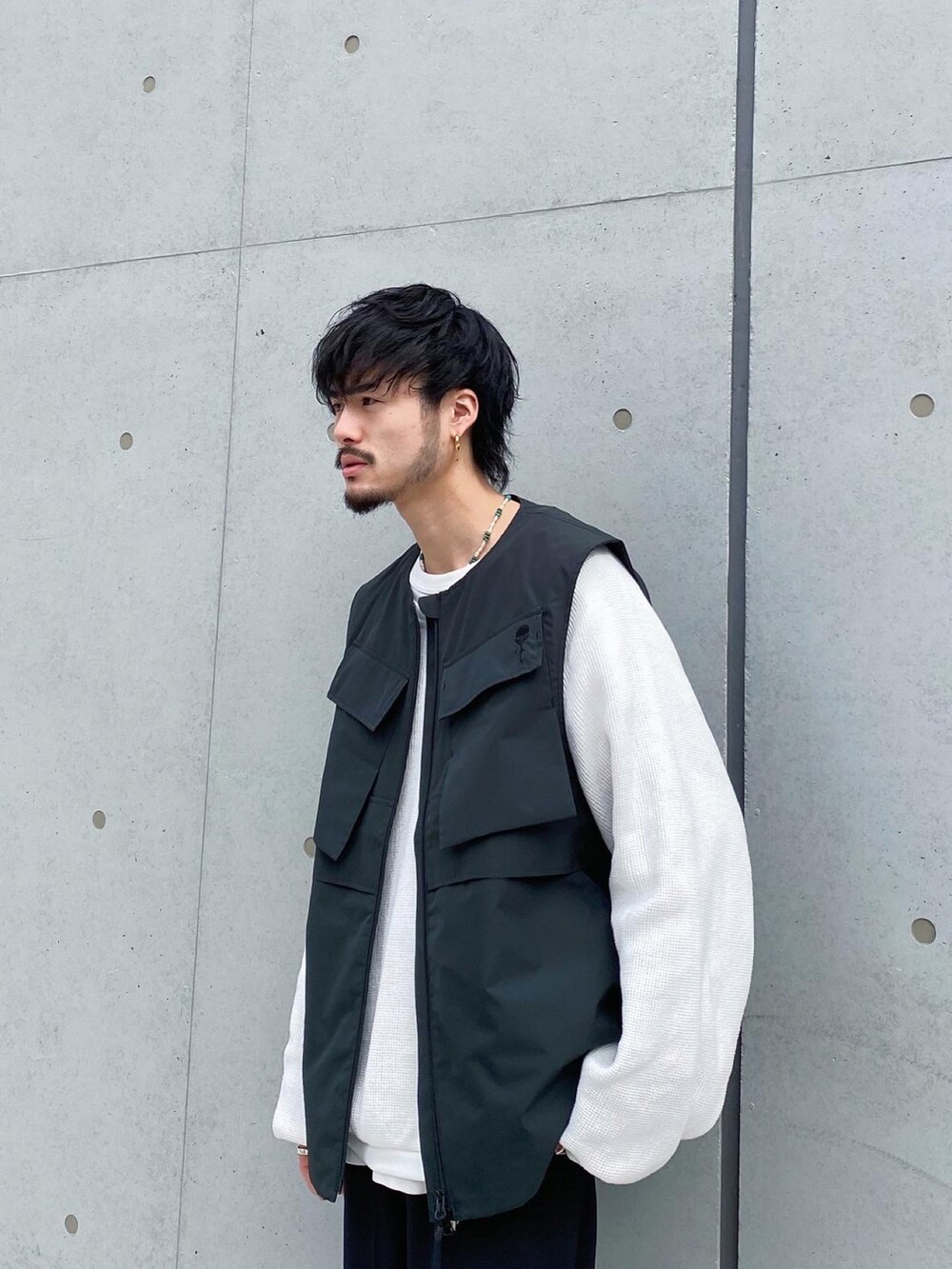 ブラック系のベスト、ブラック系のスラックス、ブラック系のブーツを着用したメンズの冬コーディネートの4枚目の写真