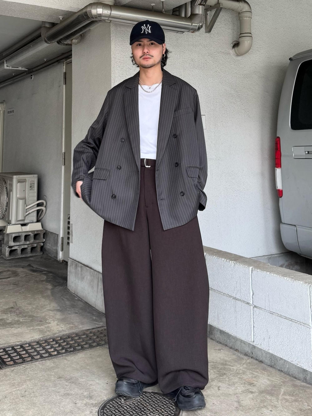 グレー系のテーラードジャケット、グレー系のスラックス、ホワイト系のTシャツ/カットソーを着用したメンズの春コーディネートの2枚目の写真