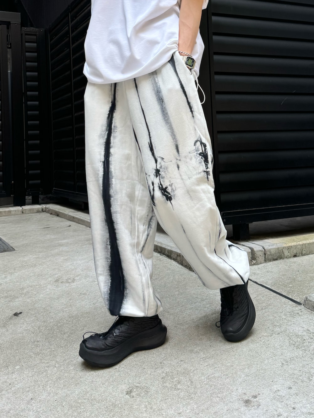 ホワイト系のTシャツ/カットソー、ホワイト系のスウェットパンツ、ブラック系のキャップを着用したメンズの夏コーディネートの4枚目の写真