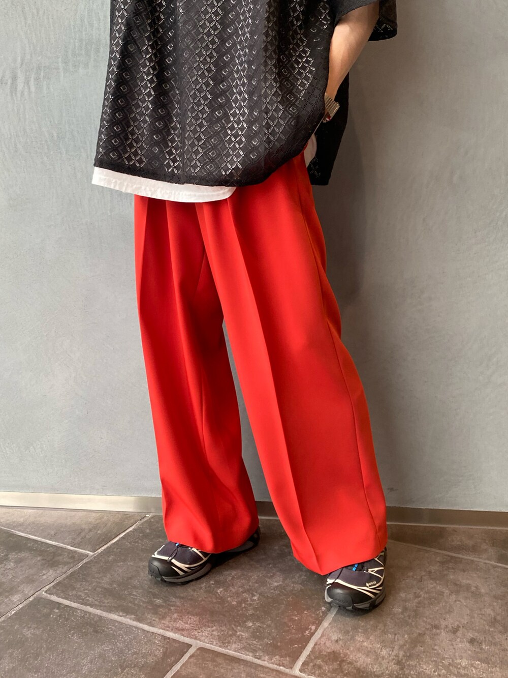 ブラック系のトップス、オレンジ系のスラックスを着用したメンズの夏コーディネートの3枚目の写真