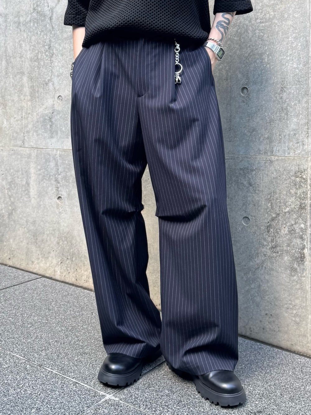 ブラック系のニット/セーター、ブラック系のその他シューズ、ブルー系のスラックスを着用したメンズの夏コーディネートの6枚目の写真
