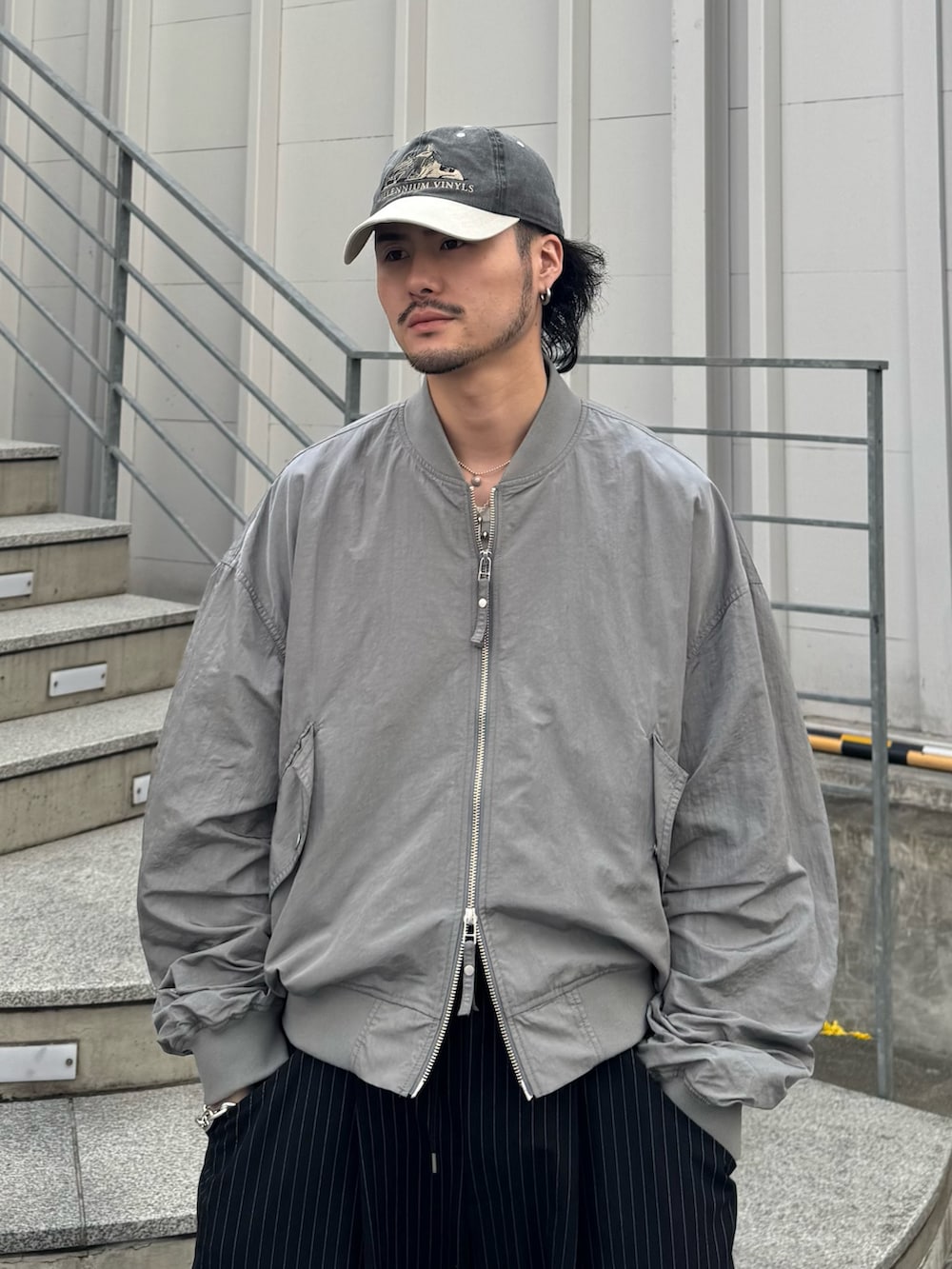 グレー系のMA-1、ブラック系のスラックスを着用したメンズの春コーディネートの4枚目の写真