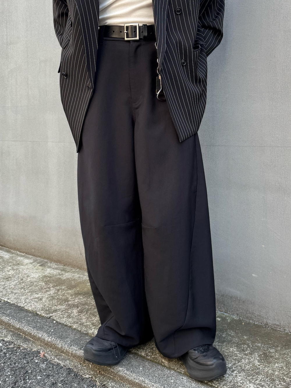 ブラック系のスラックス、ホワイト系のタンクトップ、ブラック系のテーラードジャケットを着用したメンズの春コーディネートの4枚目の写真