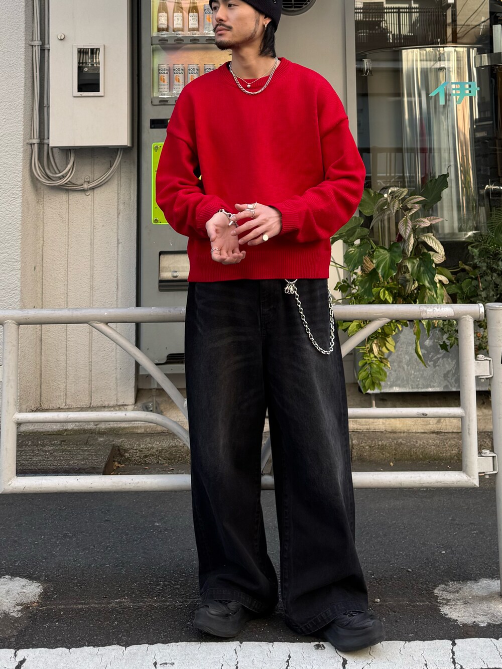 レッド系のニット/セーター、ブラック系のデニムパンツ、シルバー系の財布/小物を着用したメンズの冬コーディネートの2枚目の写真
