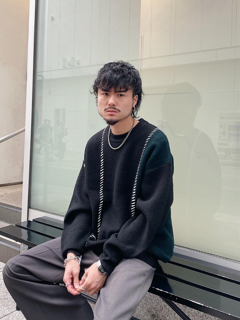 ブラック系のニット/セーター、グレー系のスラックスを着用したメンズの秋コーディネートの4枚目の写真