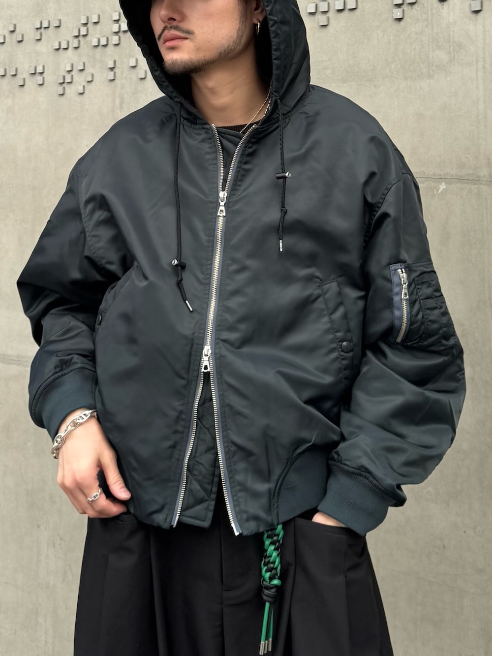 グリーン系のブルゾン、ブラック系のその他パンツ、ブラック系のキーホルダーを着用したメンズの冬コーディネートの8枚目の写真