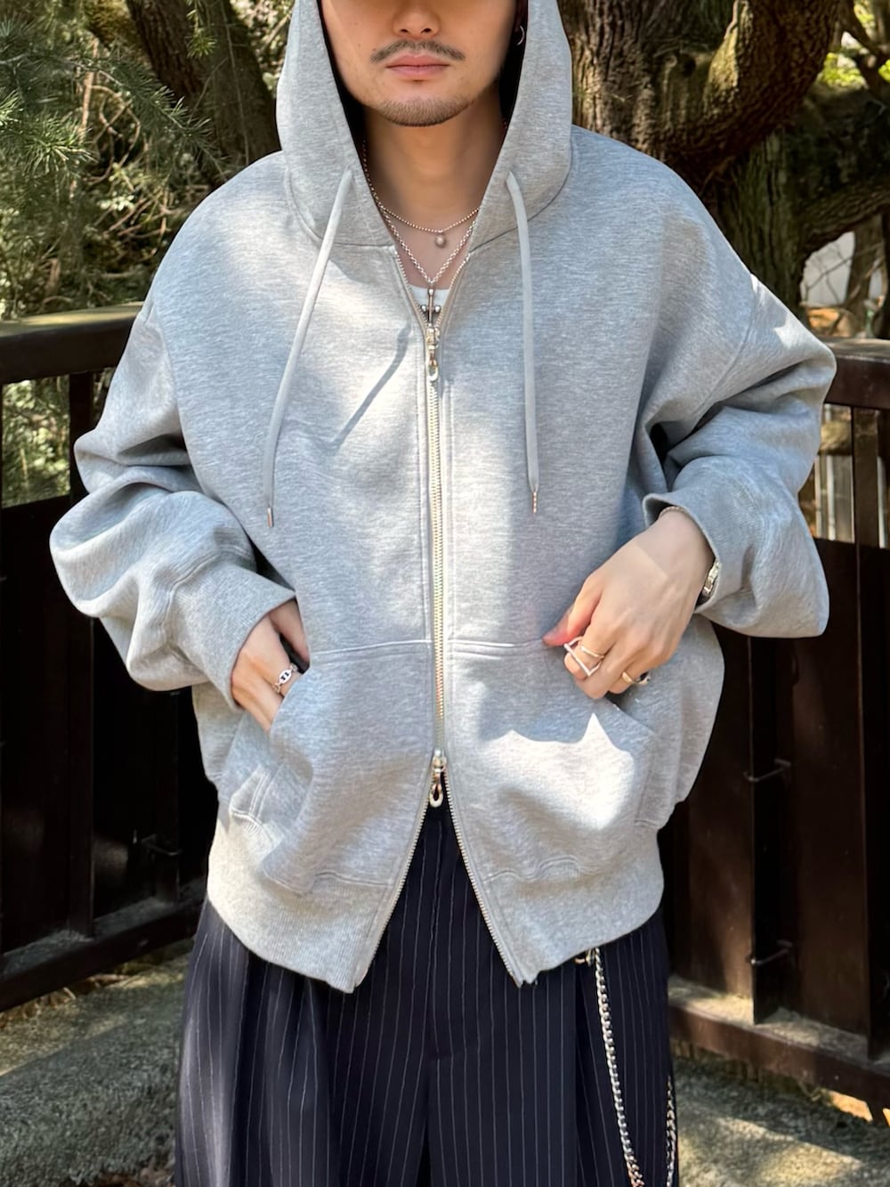 グレー系のパーカー、ブルー系のスラックス、シルバー系のウォレットチェーンを着用したメンズの春コーディネートの4枚目の写真
