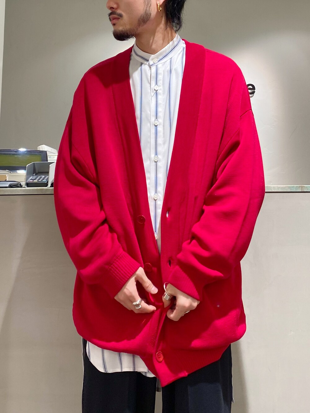 レッド系のカーディガン/ボレロ、ホワイト系のシャツ/ブラウス、ブラック系のスラックスを着用したメンズの春コーディネートの5枚目の写真