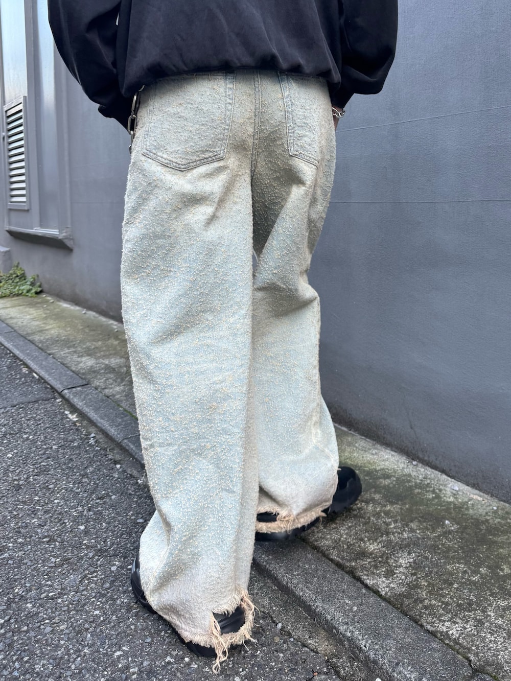 ブラック系のスウェット、ブラック系のその他シューズ、ブルー系のデニムパンツを着用したメンズの秋コーディネートの7枚目の写真