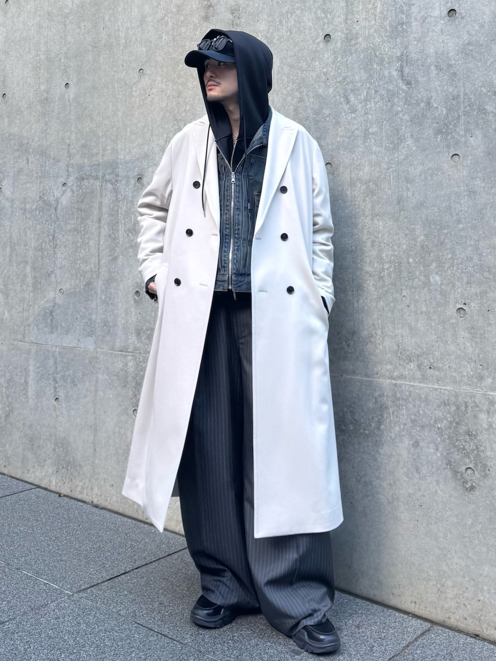 グレー系のチェスターコート、ブルー系のデニムジャケット、ブラック系のパーカーを着用したメンズの冬コーディネートの2枚目の写真