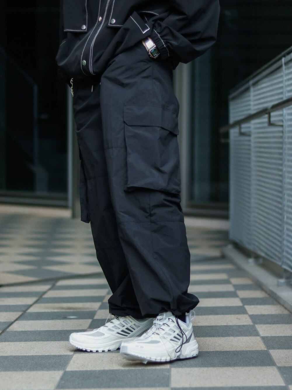 ブラック系のブルゾン、ブラック系のカーゴパンツ、ホワイト系のスニーカーを着用したメンズの春コーディネートの3枚目の写真