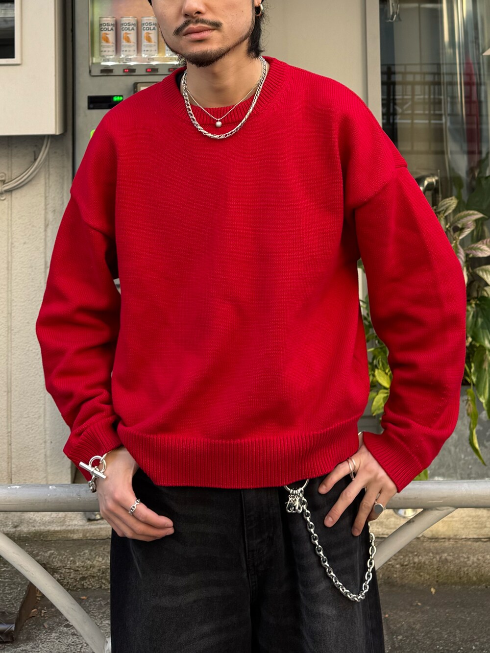 レッド系のニット/セーター、ブラック系のデニムパンツ、シルバー系の財布/小物を着用したメンズの冬コーディネートの3枚目の写真