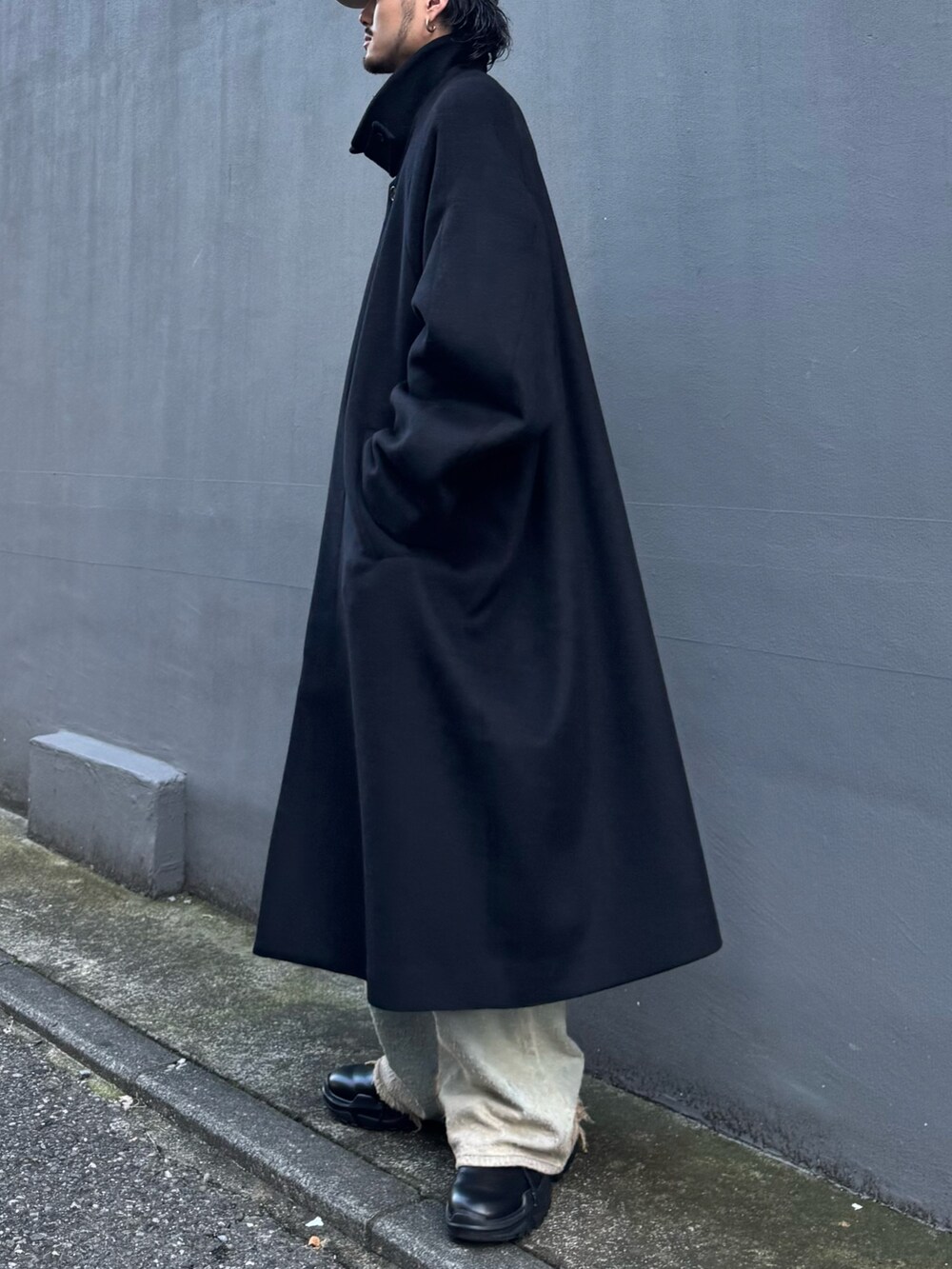 ブルー系のニット/セーター、ブルー系のデニムパンツ、ブラック系のステンカラーコートを着用したメンズの秋コーディネートの6枚目の写真
