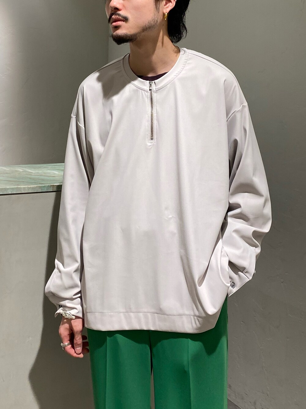 グレー系のTシャツ/カットソー、グリーン系のスラックスを着用したメンズの春コーディネートの3枚目の写真