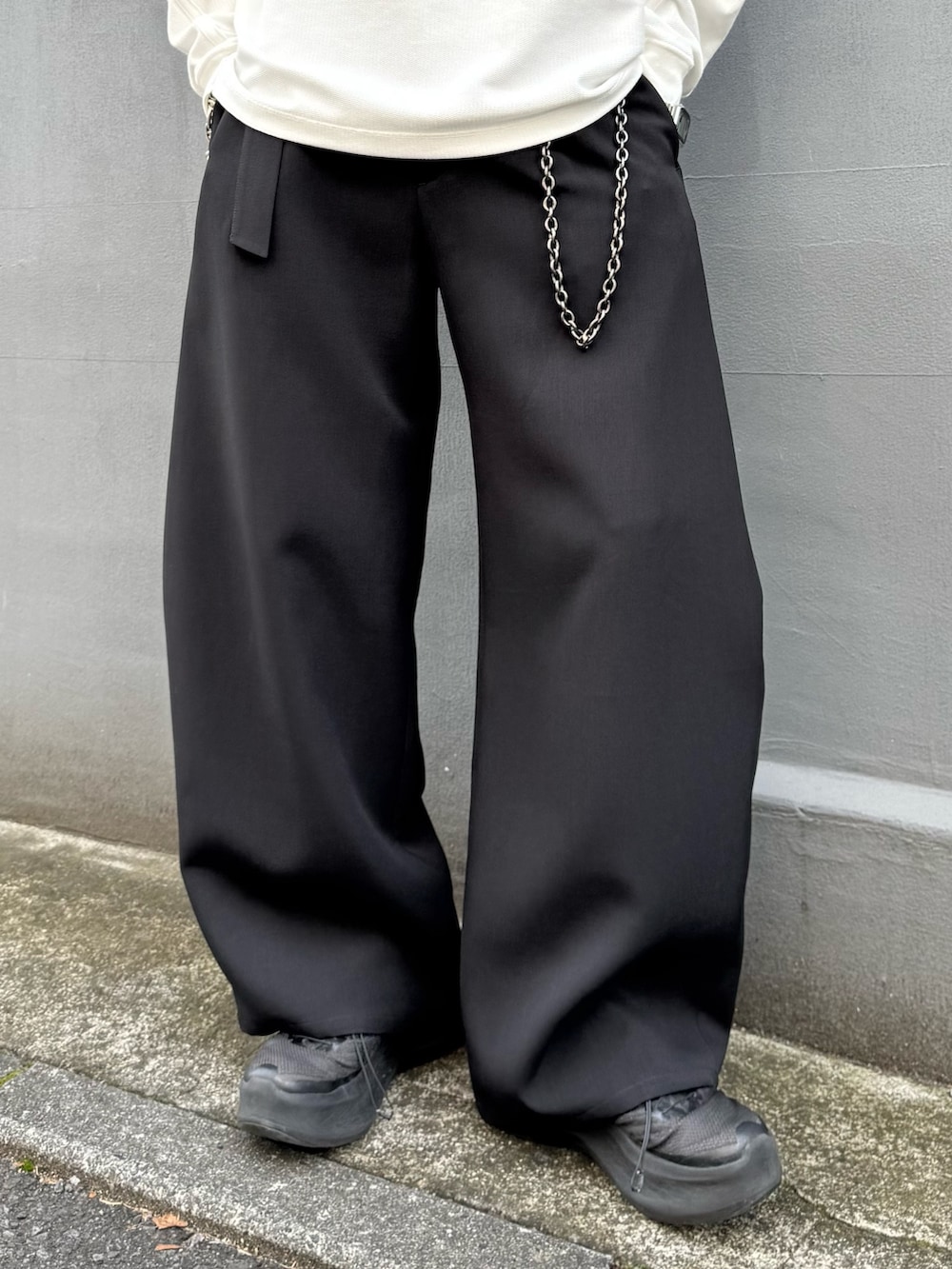 ホワイト系のTシャツ/カットソー、ブラック系のスラックス、ブラック系のウォレットチェーンを着用したメンズの春コーディネートの6枚目の写真