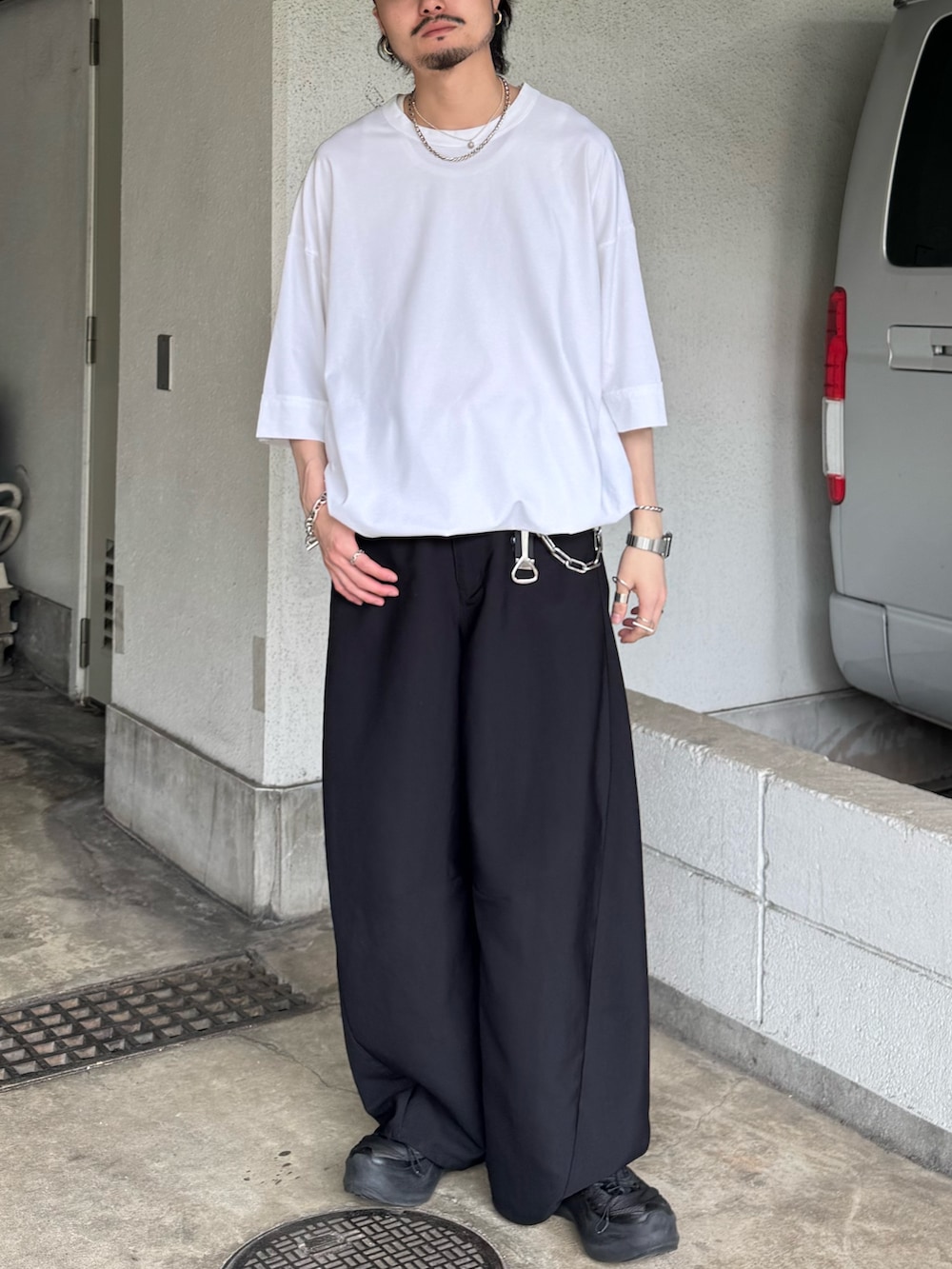 ホワイト系のTシャツ/カットソー、ブラック系のスラックスを着用したメンズの夏コーディネートの2枚目の写真