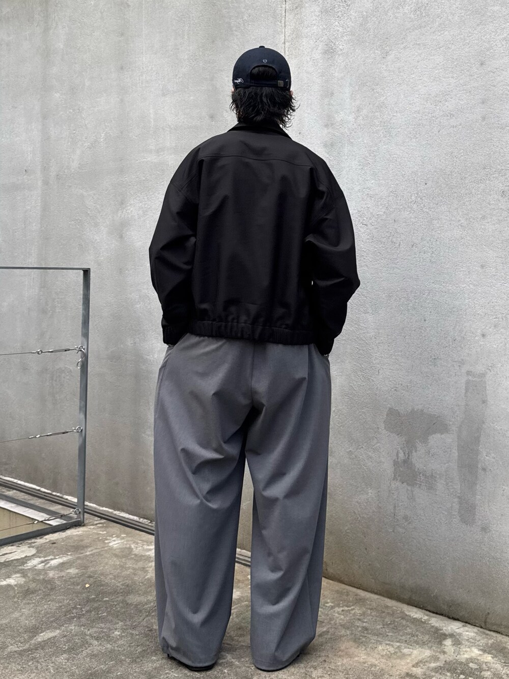 ブラック系のブルゾン、グレー系のスラックスを着用したメンズの秋コーディネートの3枚目の写真