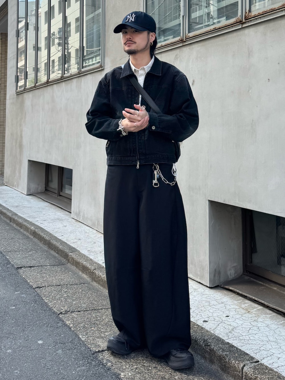 ブラック系のスラックス、ブラック系のショルダーバッグ、ホワイト系のシャツ/ブラウスを着用したメンズの春コーディネートの2枚目の写真