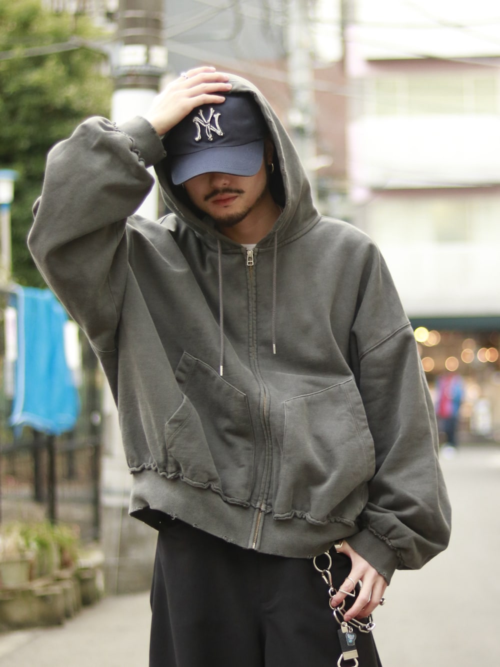 グレー系のパーカー、ブラック系のスラックス、ブラック系のキーホルダーを着用したメンズの冬コーディネートの4枚目の写真