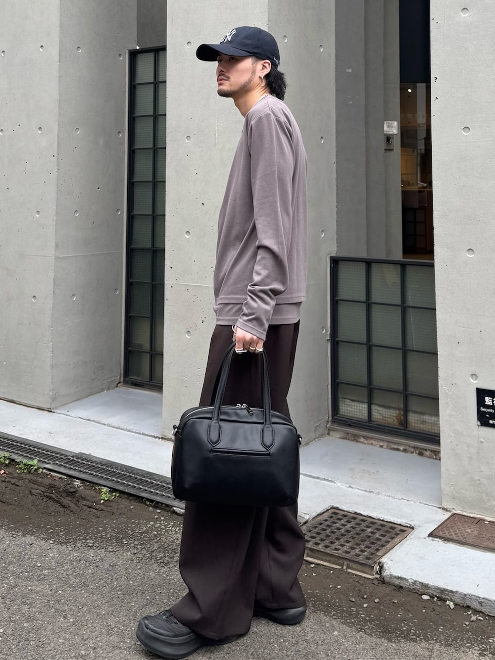 グレー系のスラックス、グレー系のTシャツ/カットソー、ブラック系のショルダーバッグを着用したメンズの春コーディネートの2枚目の写真