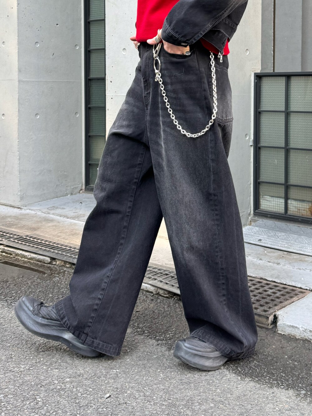 ブラック系のブルゾン、ブラック系のデニムパンツ、レッド系のニット/セーターを着用したメンズの冬コーディネートの5枚目の写真
