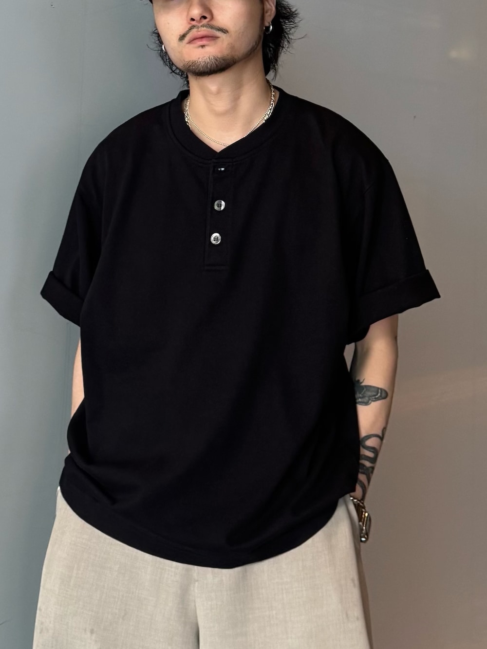 ブラック系のTシャツ/カットソー、ベージュ系のスラックスを着用したメンズの春コーディネートの6枚目の写真
