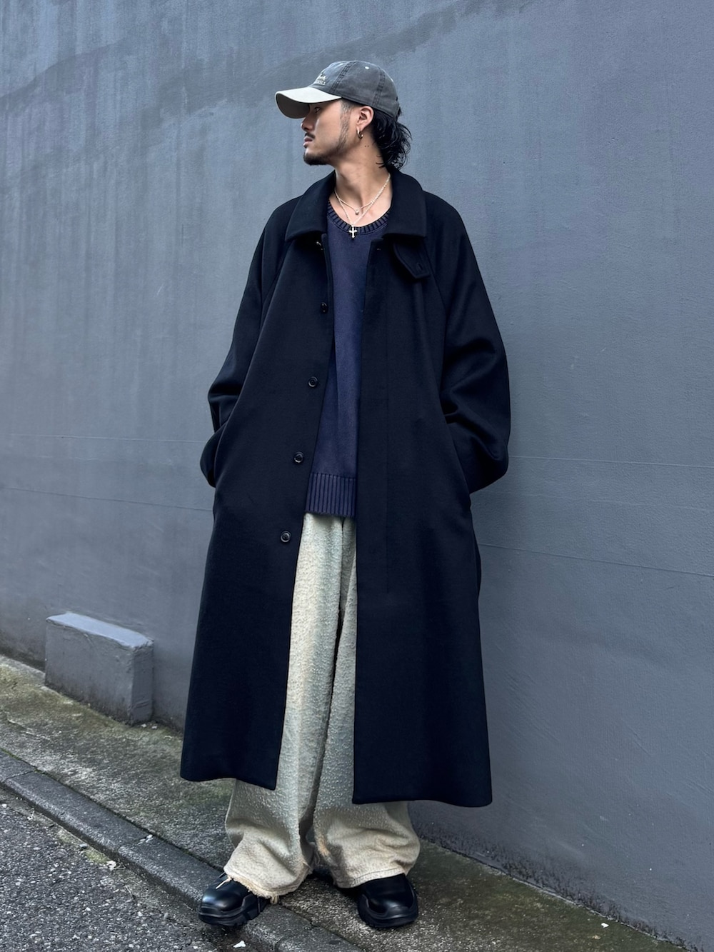 ブルー系のニット/セーター、ブルー系のデニムパンツ、ブラック系のステンカラーコートを着用したメンズの秋コーディネートの2枚目の写真
