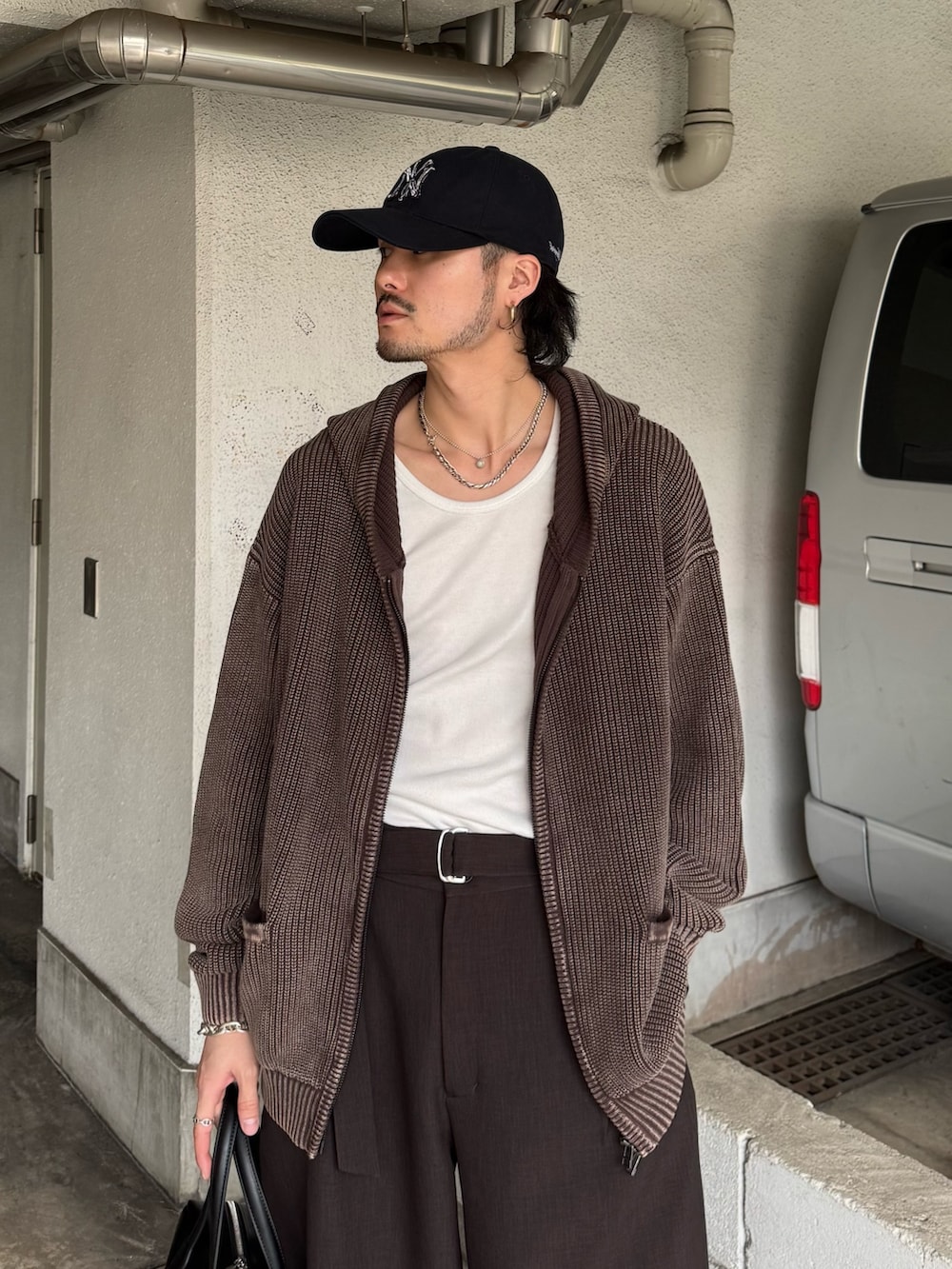 ブラウン系のパーカー、グレー系のスラックス、ブラック系のショルダーバッグを着用したメンズの春コーディネートの7枚目の写真