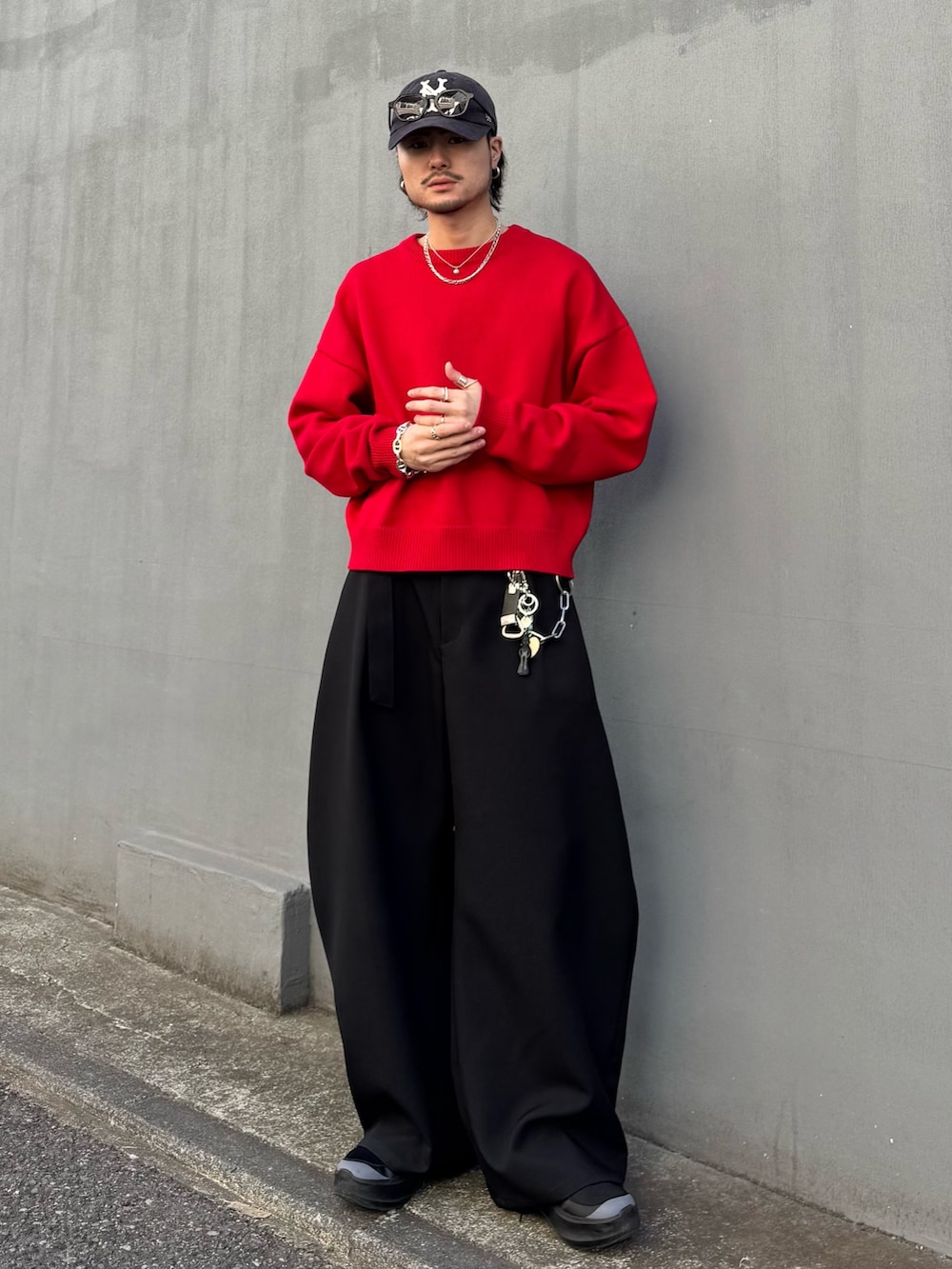 レッド系のニット/セーター、ブラック系のスラックスを着用したメンズの冬コーディネートの2枚目の写真