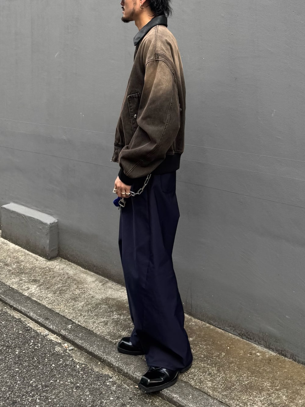 ブラウン系のデニムジャケット、ブルー系のスラックス、ブルー系のキャップを着用したメンズの秋コーディネートの3枚目の写真