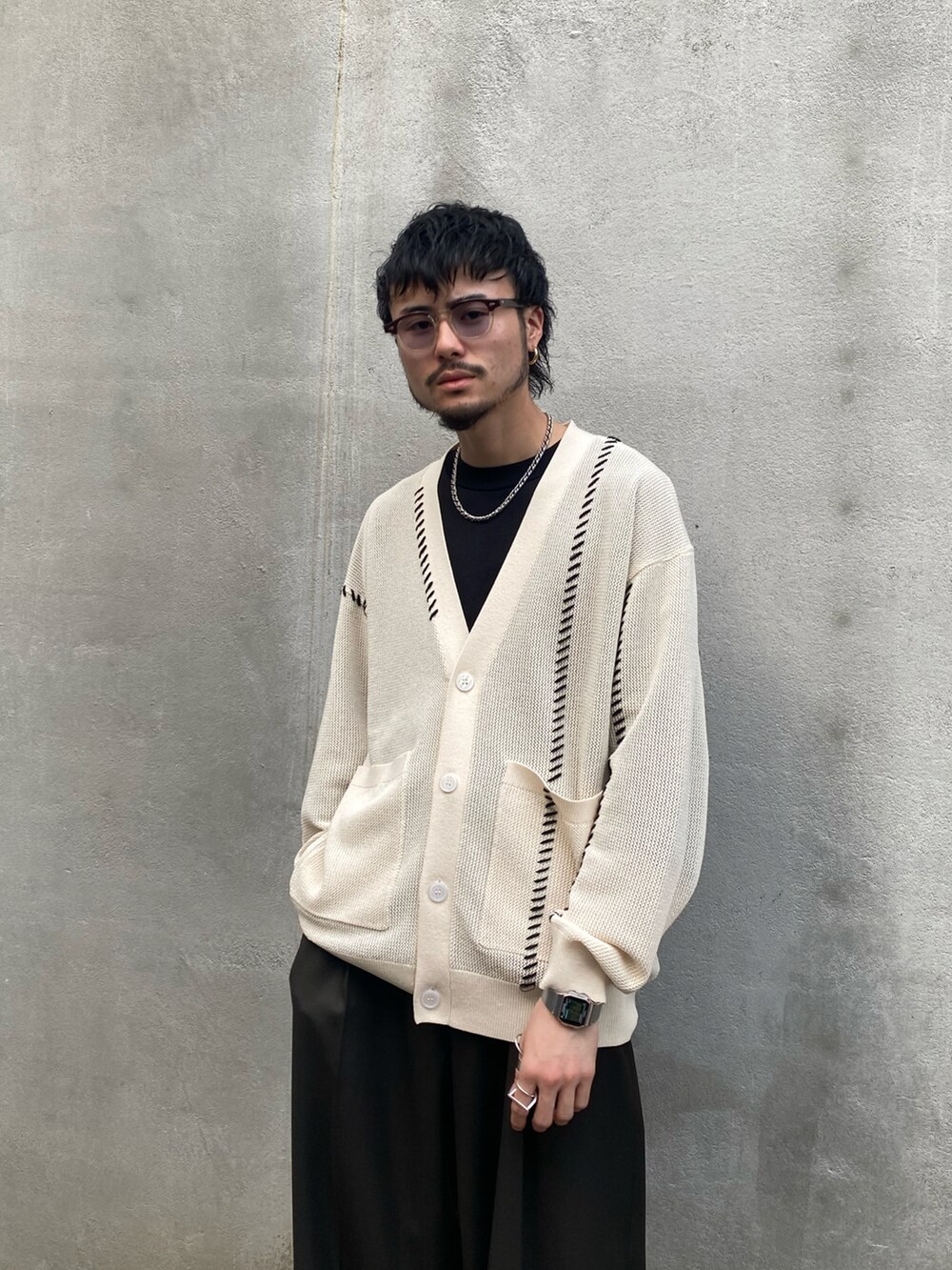 ホワイト系のカーディガン/ボレロ、グリーン系のスラックス、ブラック系のドレスシューズを着用したメンズの春コーディネートの2枚目の写真