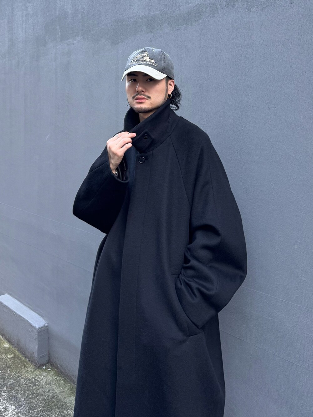 ブルー系のニット/セーター、ブルー系のデニムパンツ、ブラック系のステンカラーコートを着用したメンズの秋コーディネートの9枚目の写真