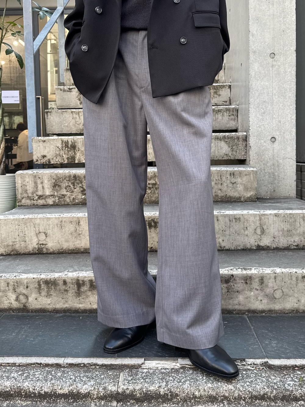 ブラック系のテーラードジャケット、ブラック系のニット/セーター、グレー系のスラックスを着用したメンズの春コーディネートの4枚目の写真