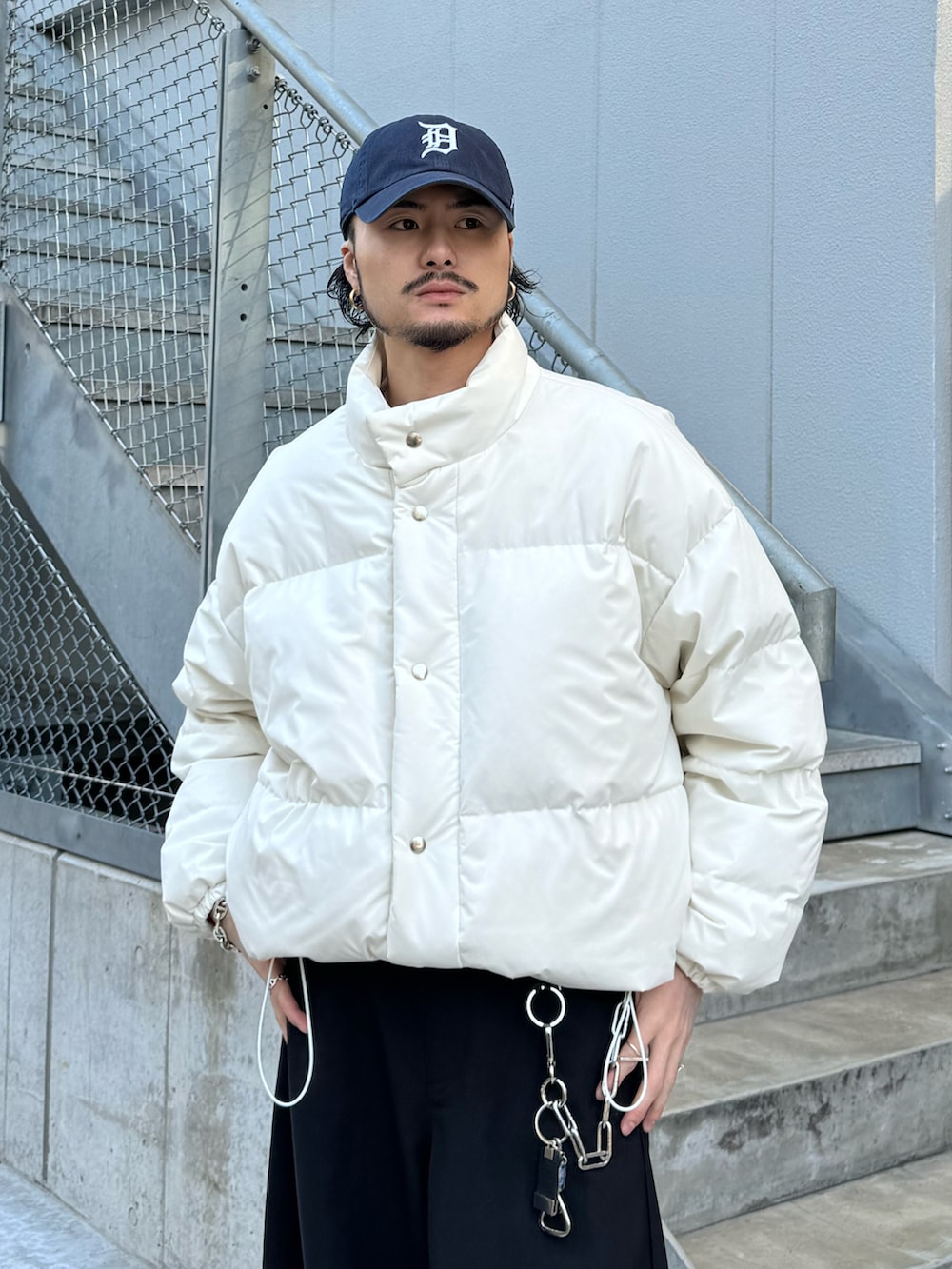 ホワイト系のブルゾン、ブラック系のスラックス、レッド系のニット/セーターを着用したメンズの冬コーディネートの4枚目の写真