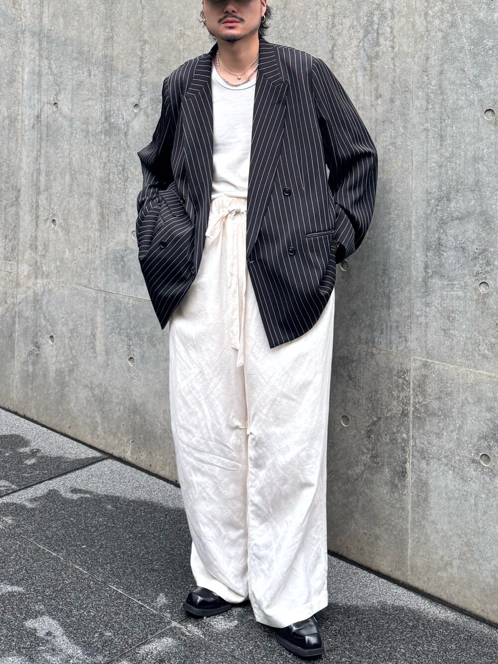 ブラック系のテーラードジャケット、ホワイト系のタンクトップ、ホワイト系のその他パンツを着用したメンズの夏コーディネートの2枚目の写真