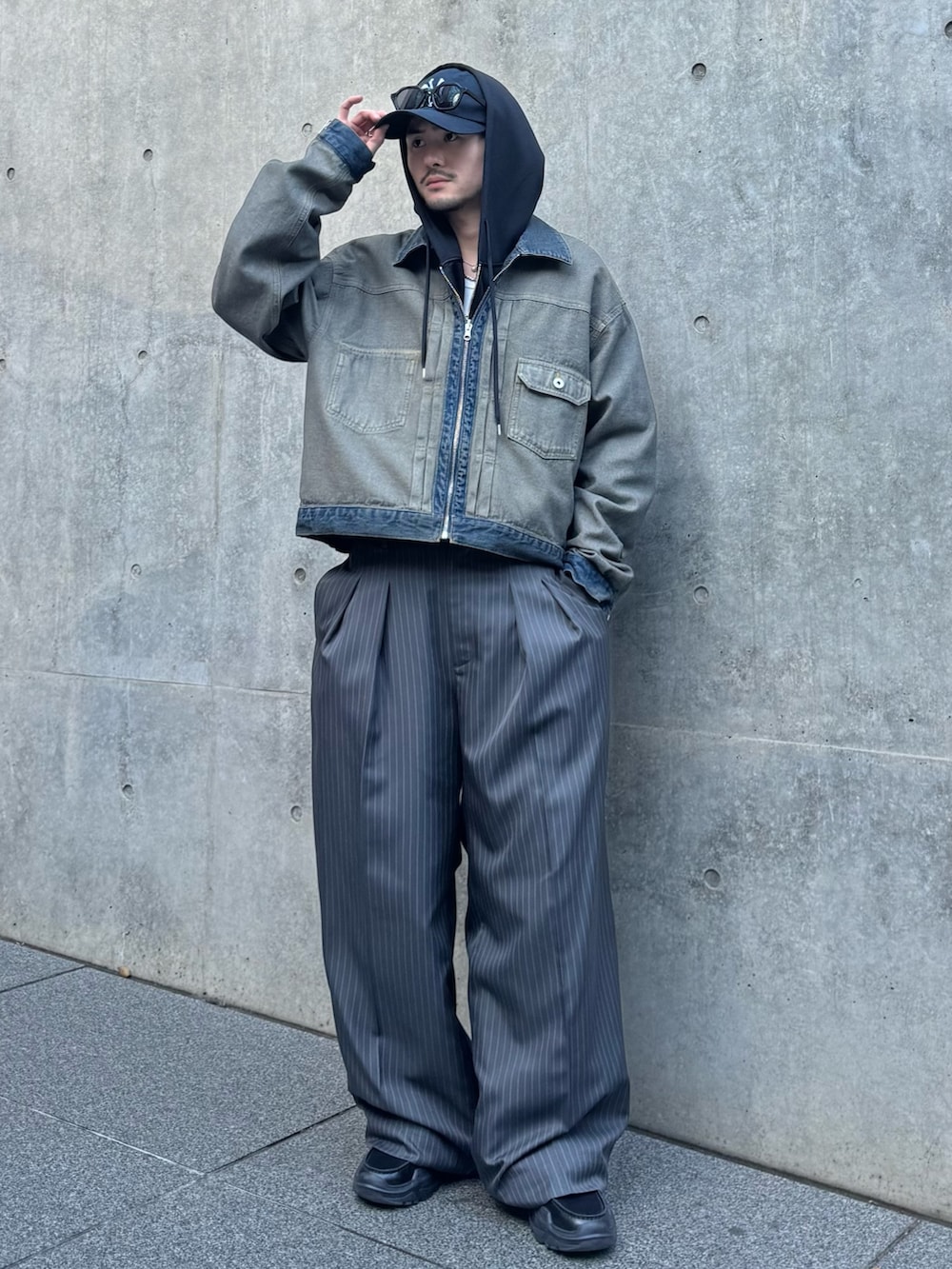 ブラック系のパーカー、ブルー系のデニムジャケット、グレー系のスラックスを着用したメンズの冬コーディネートの2枚目の写真