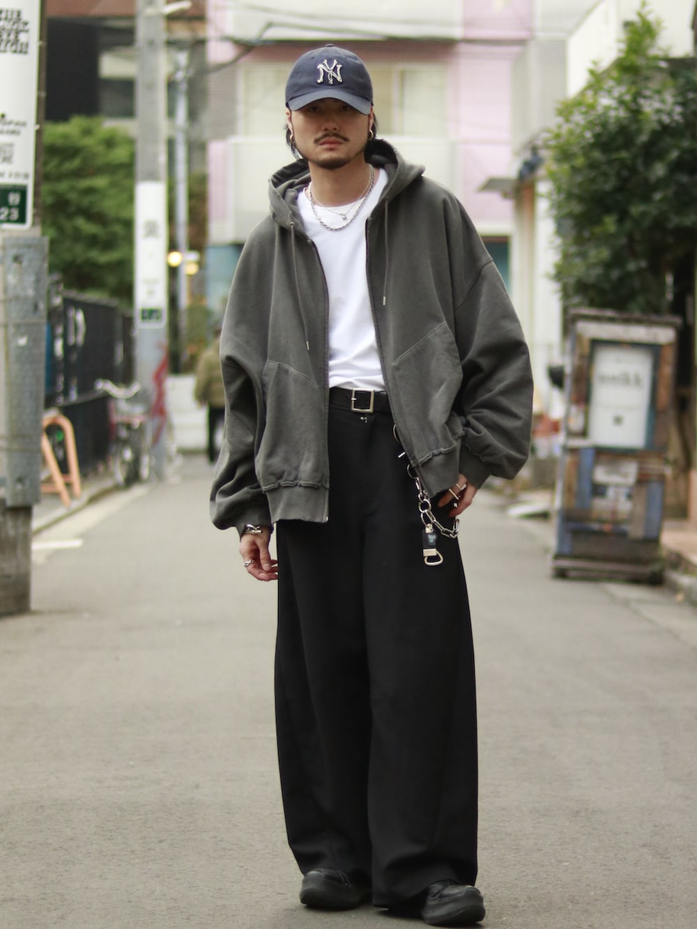 グレー系のパーカー、ブラック系のスラックス、ブラック系のキーホルダーを着用したメンズの冬コーディネートの2枚目の写真