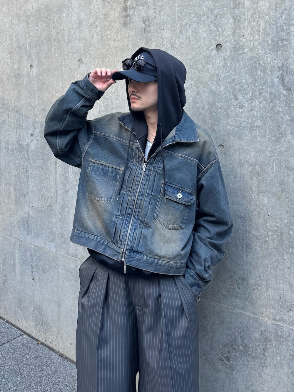 ブラック系のパーカー、ブルー系のデニムジャケット、グレー系のスラックスを着用したメンズの冬コーディネートの6枚目の写真